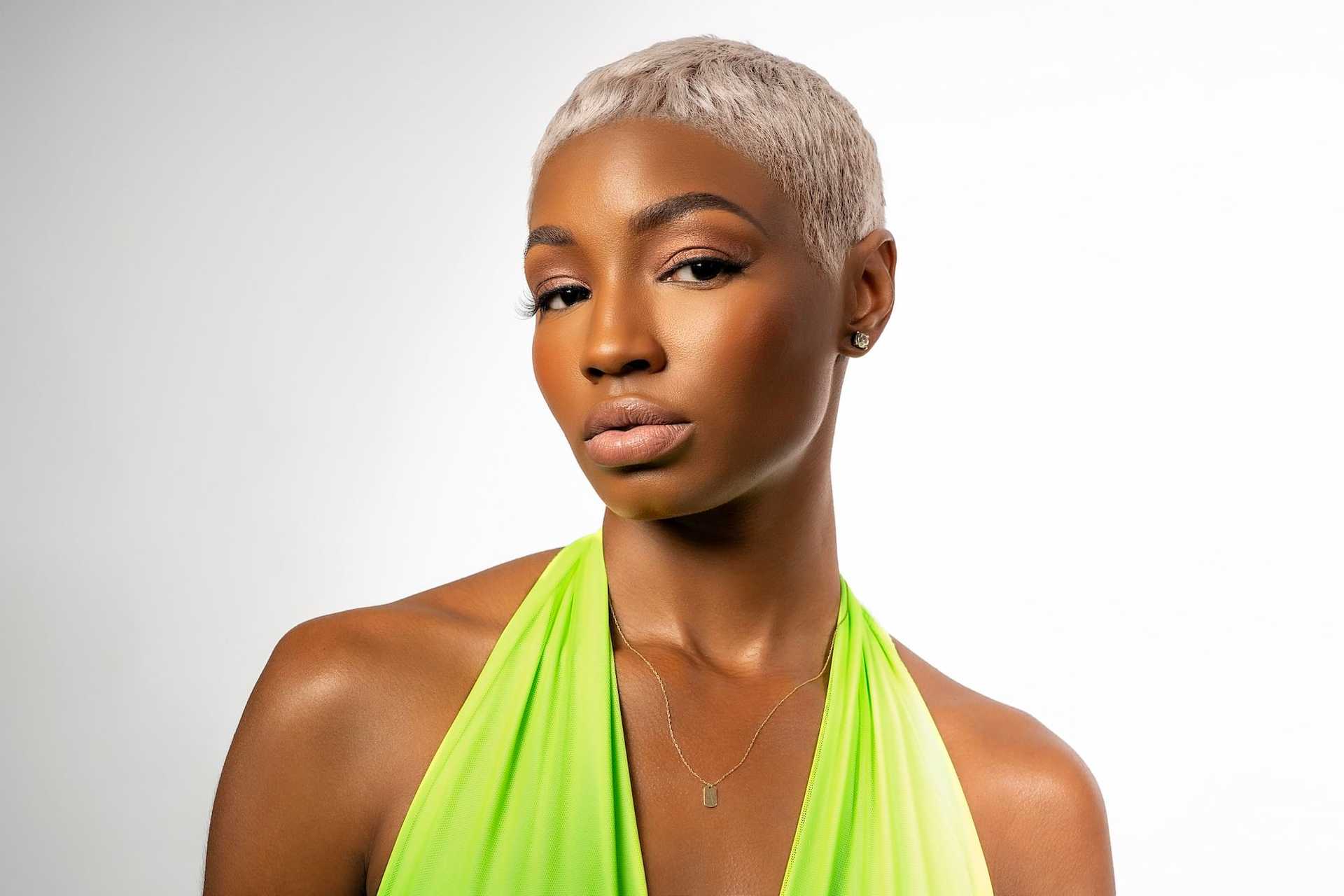 Short-haired woman in a green halter top against a white background.