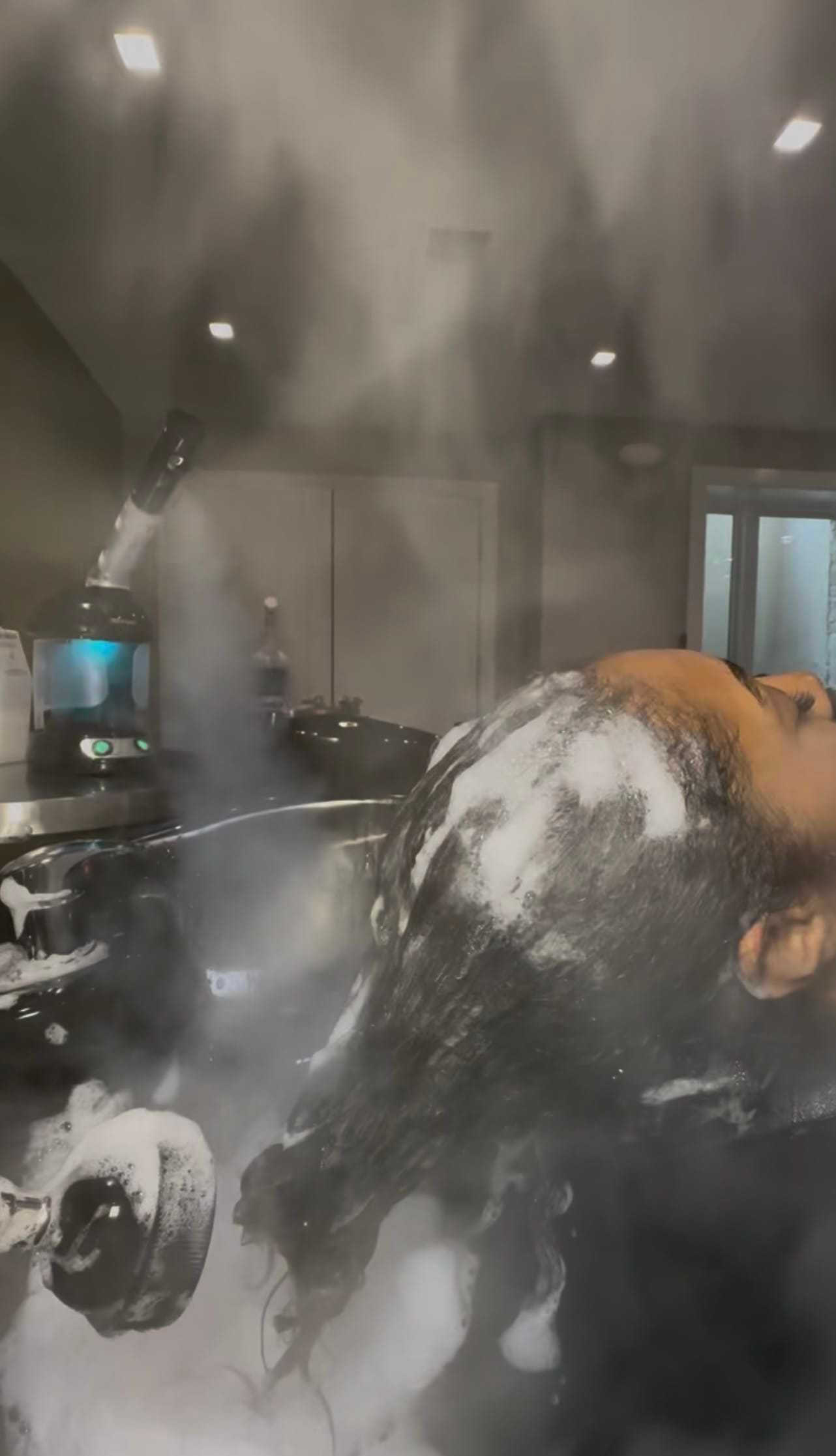 Steam treatment applied to hair with foamy shampoo at a salon.