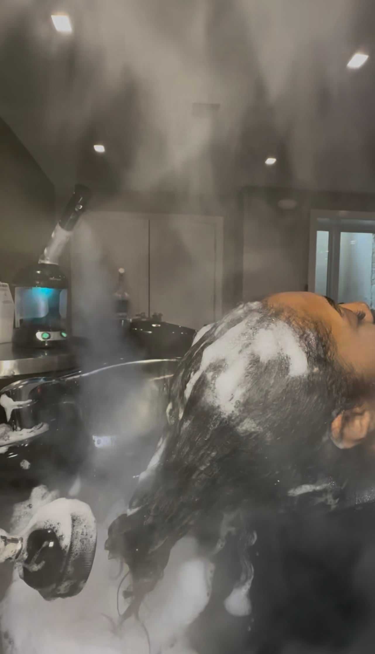 Steam treatment applied to hair with foamy shampoo at a salon.