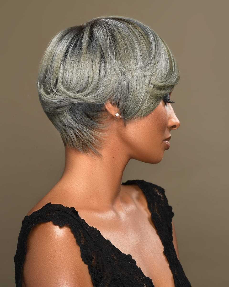 Short-haired woman with ash gray bob, wearing a black lace top, looking to the side.