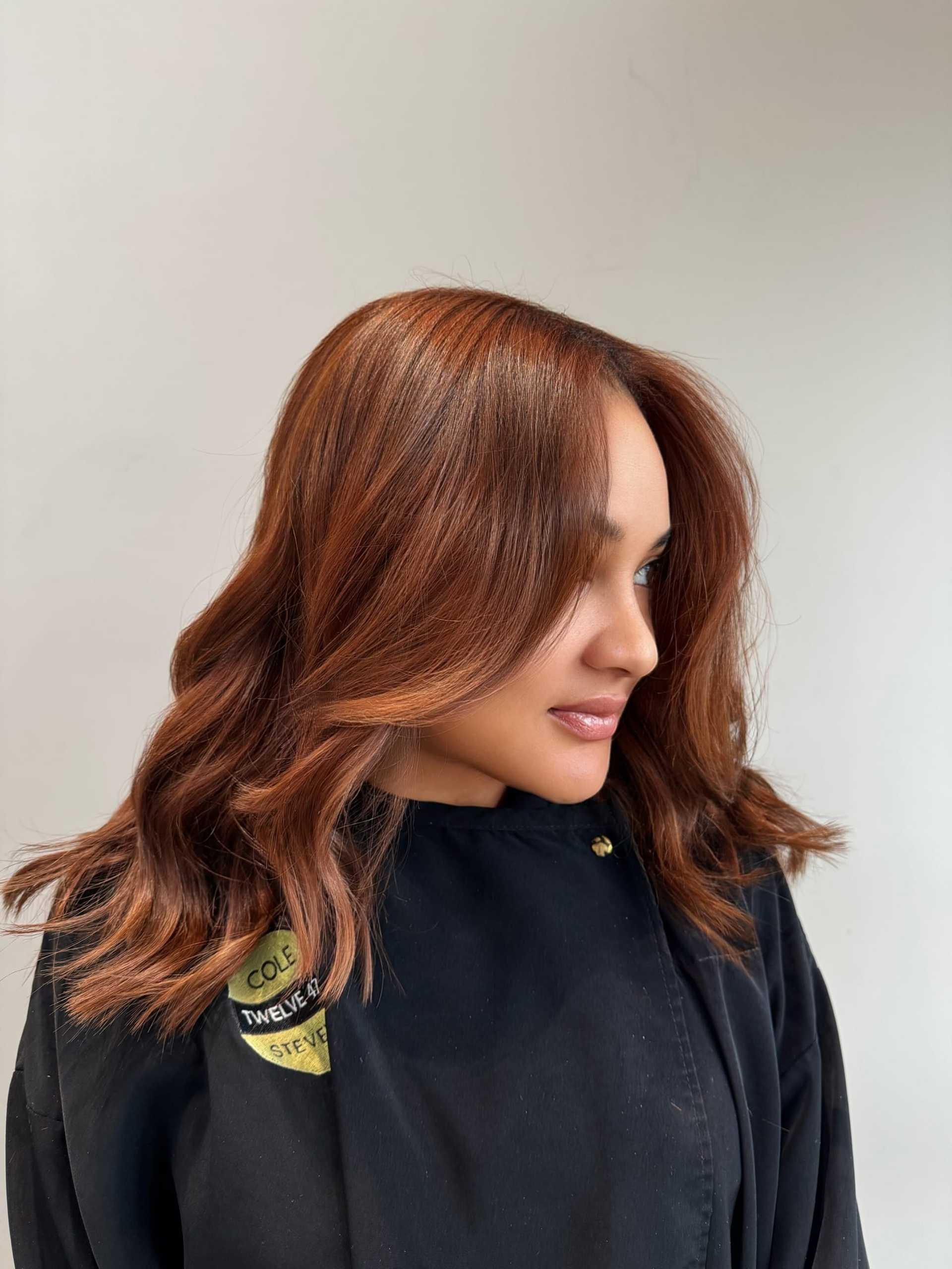 Brown-haired woman with styled waves, smiling gently and wearing a black outfit.